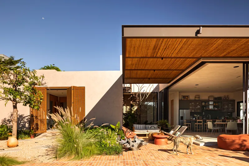 Courtyard terrace with timber overhang and perforated wood screens beside a planted garden bed