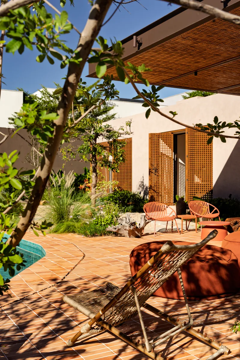 Interior courtyard with terracotta tile paving and mesh seating beneath fruit tree branches