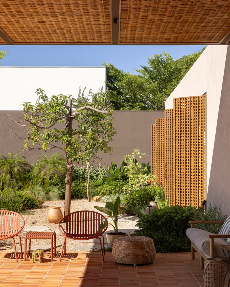 Enclosed courtyard with lattice screen and woven ceiling panel over terracotta tile terrace