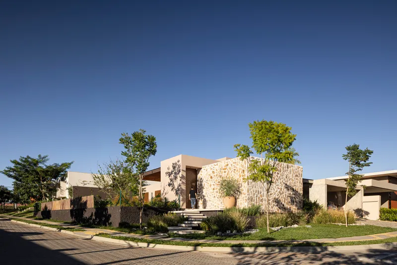 Corner lot view showing the curved stone facade and planted front yard with young trees