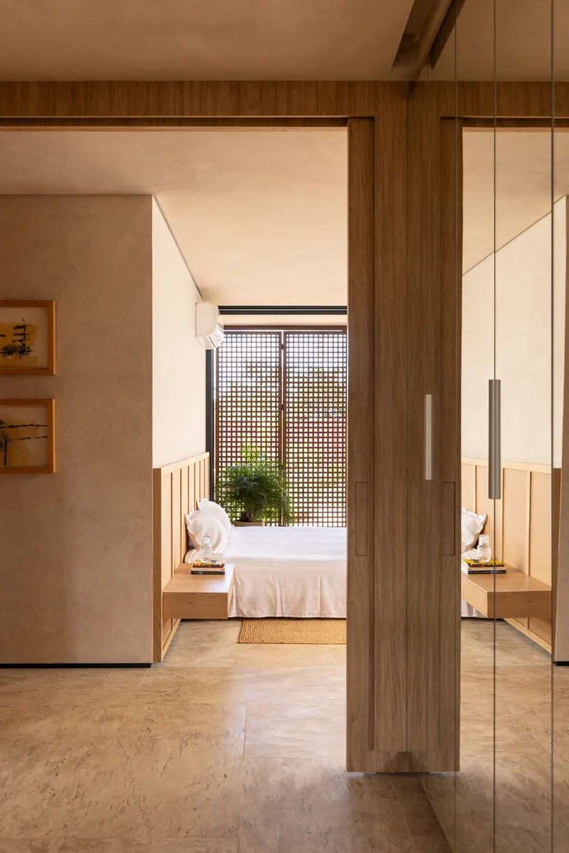 Interior corridor view through timber doorframe toward bedroom with gridded screen beyond