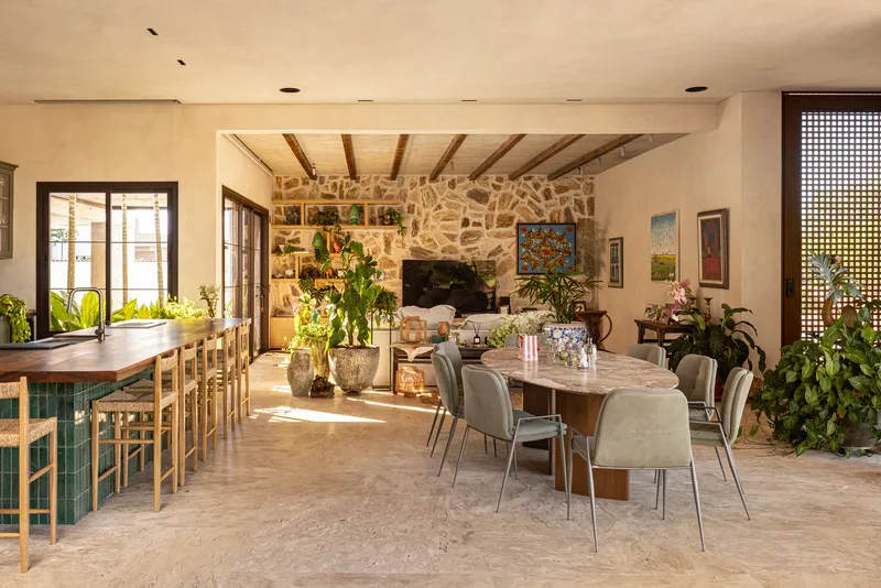 Open living and dining room with stone fireplace wall and exposed timber ceiling beams