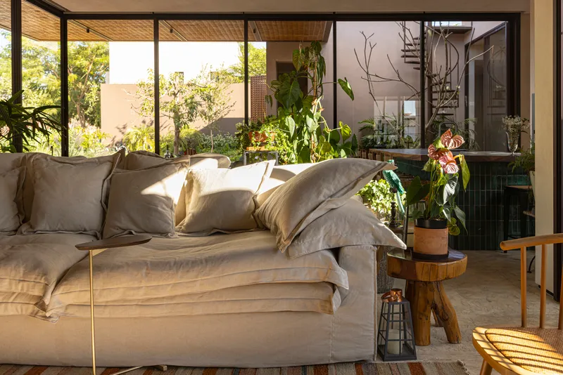 Living room with woven ceiling and full-height glazing opening to a planted interior courtyard