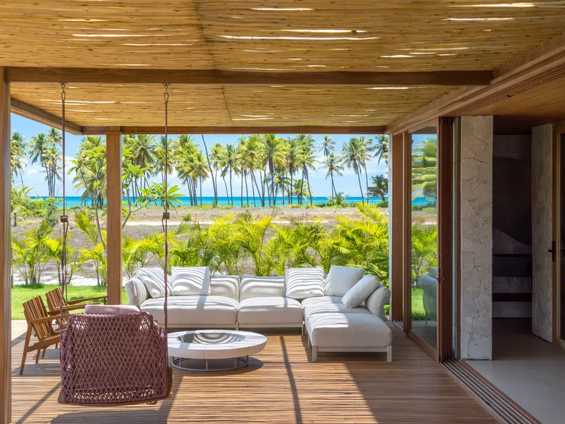Covered deck with seating area overlooking palms and ocean under a slatted timber ceiling