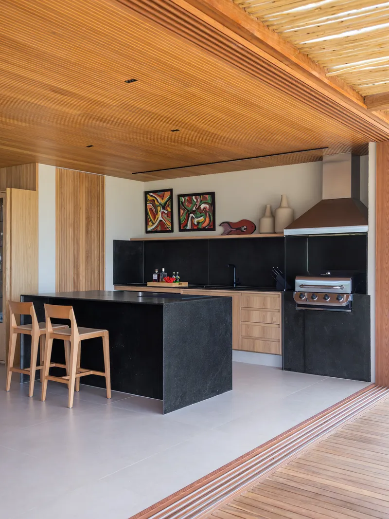Kitchen with black stone island and timber cabinetry opening to an exterior timber deck