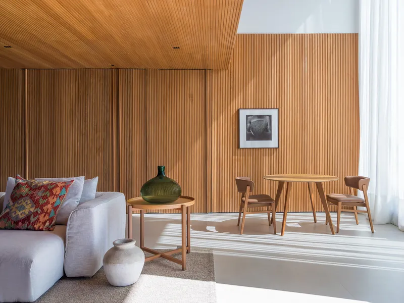 Living area with vertical timber wall panels and afternoon sunlight striping the polished concrete floor