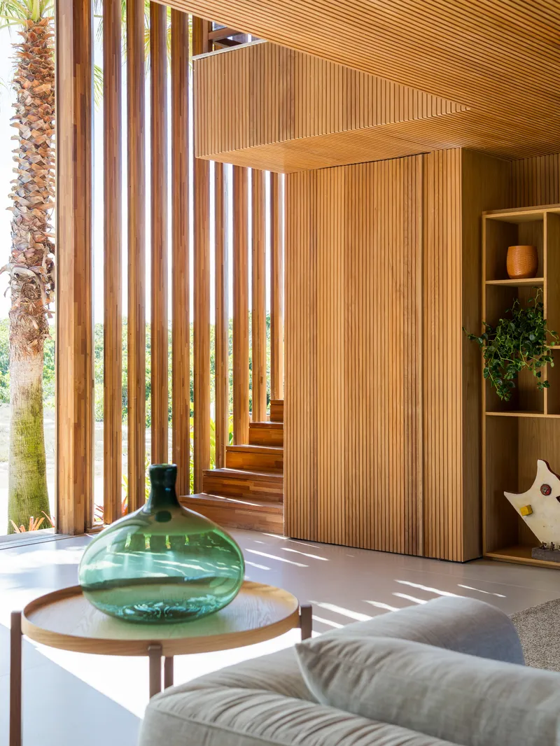 Timber staircase with slatted screening next to vertical wood slat brise-soleil filtering afternoon sunlight