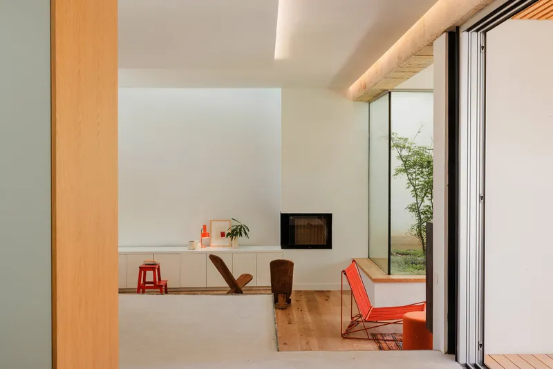 View through sliding doors to living area with inset fireplace and glazed courtyard beyond