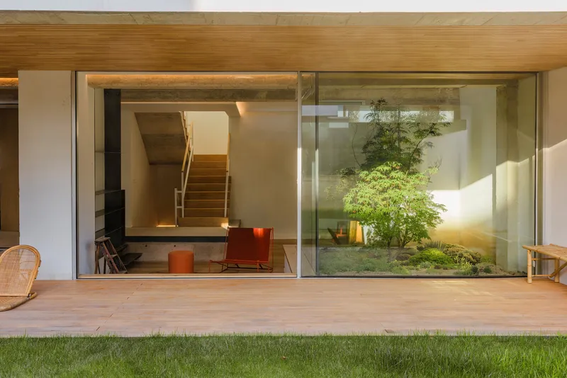 Timber-framed opening with sliding glass doors looking into a living space and internal courtyard with greenery