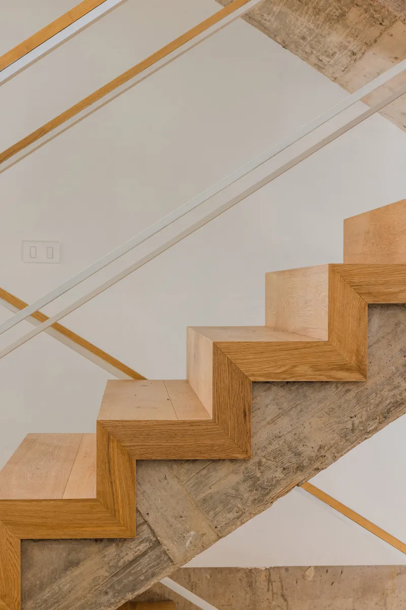 Angled view of oak stair treads turning around the raw concrete stair structure