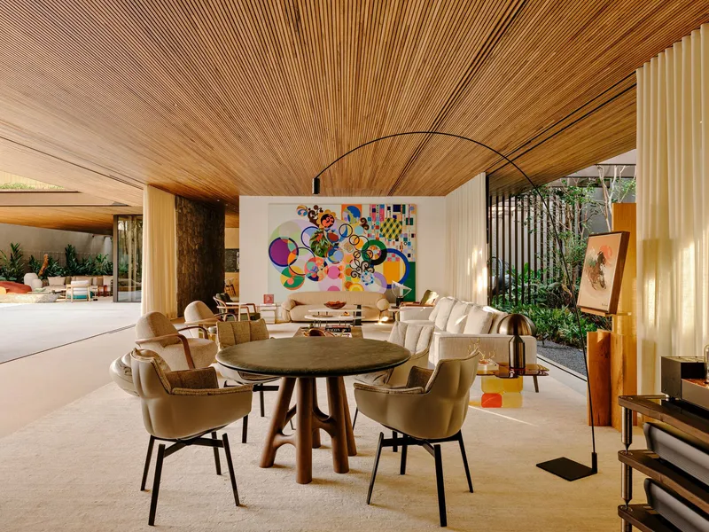 Dining area beneath timber slat ceiling with vertical screen dividing interior courtyard garden