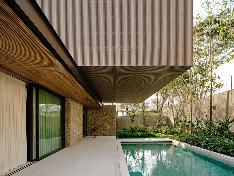 Poolside terrace with slatted timber soffit overhang and stone boundary wall