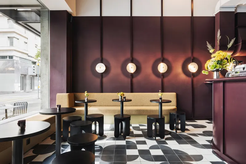 Interior seating area with burgundy paneled wall featuring circular pendant lights and checkered tile floor