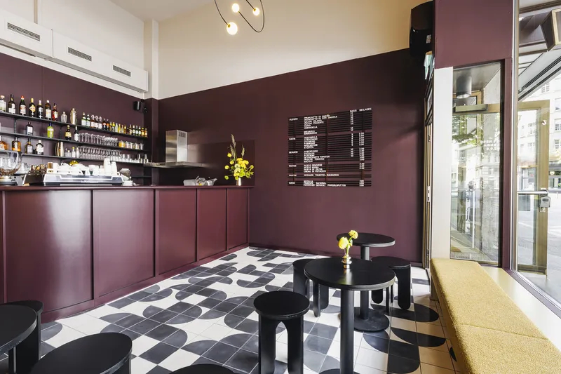 Corner counter with burgundy paneling and wall-mounted menu board above the geometric floor pattern