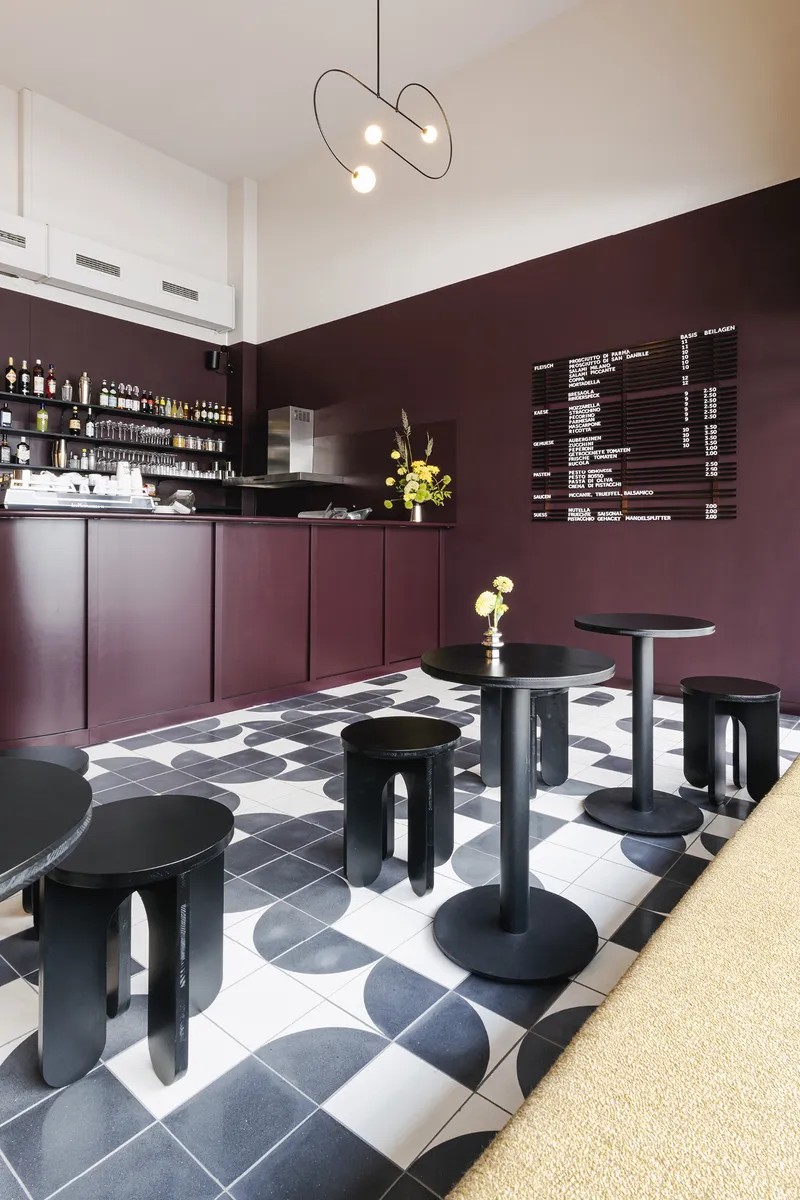 Service counter with burgundy cabinetry and tiled floor leading toward shelved bar display