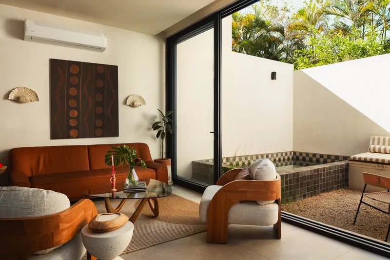 Living room opening to a tiled courtyard terrace through a sliding glass door in afternoon light