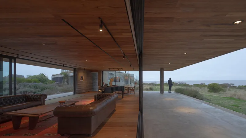 Living room opening to covered terrace with timber soffit and a person visible on the outdoor deck