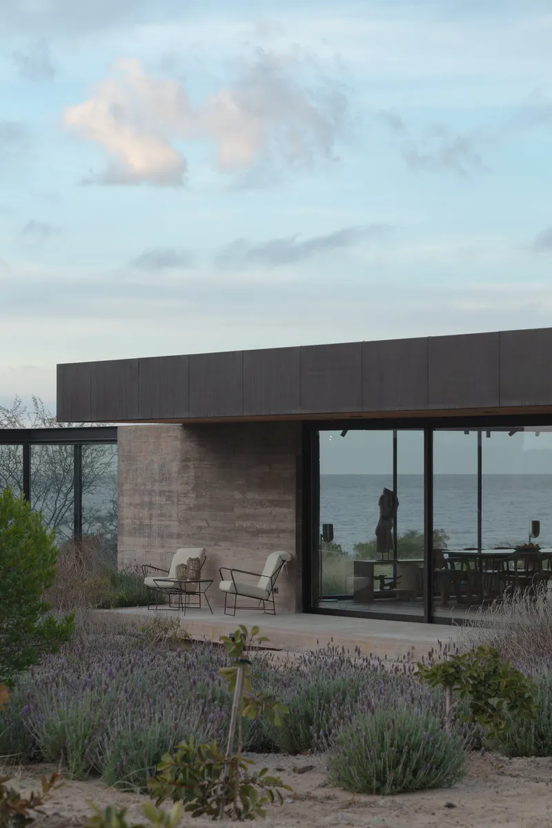 Covered patio with seating overlooking the ocean framed by native plantings at dusk
