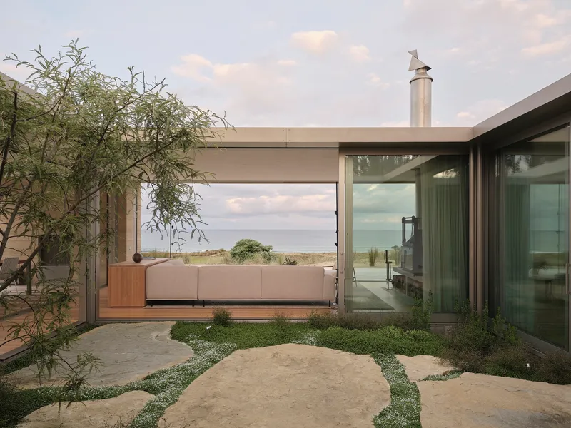 Internal courtyard with limestone pavers and planted groundcover framed by glass walls and concrete beams