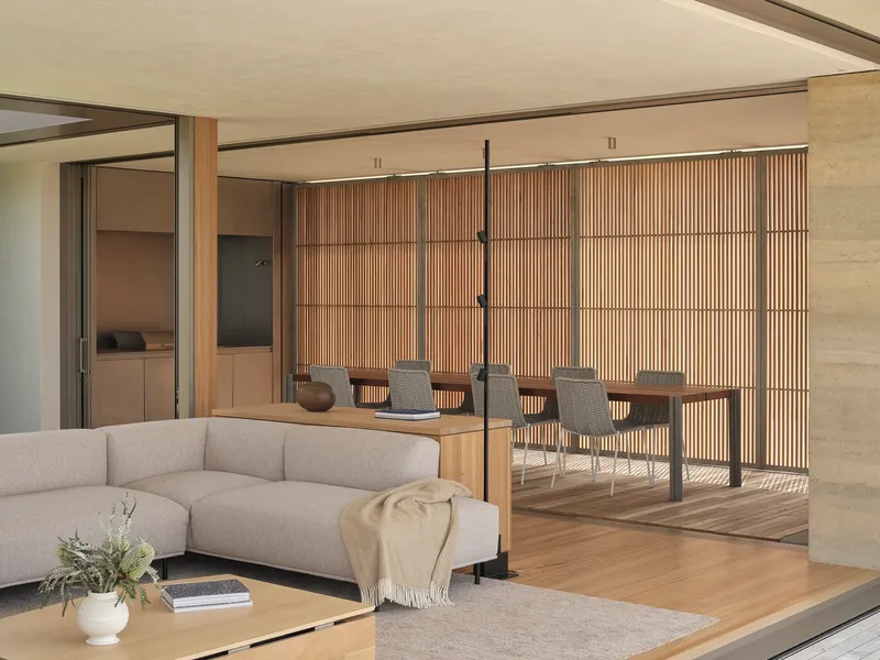 Living space opening to outdoor dining terrace with slatted timber screen and suspended black pendant light