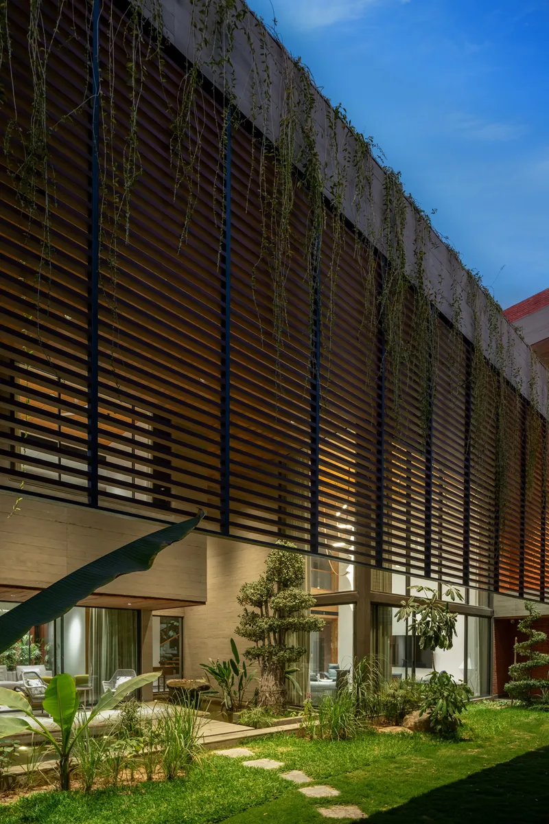 Courtyard garden with stepping stone path beneath horizontal slatted screen with cascading vines at dusk