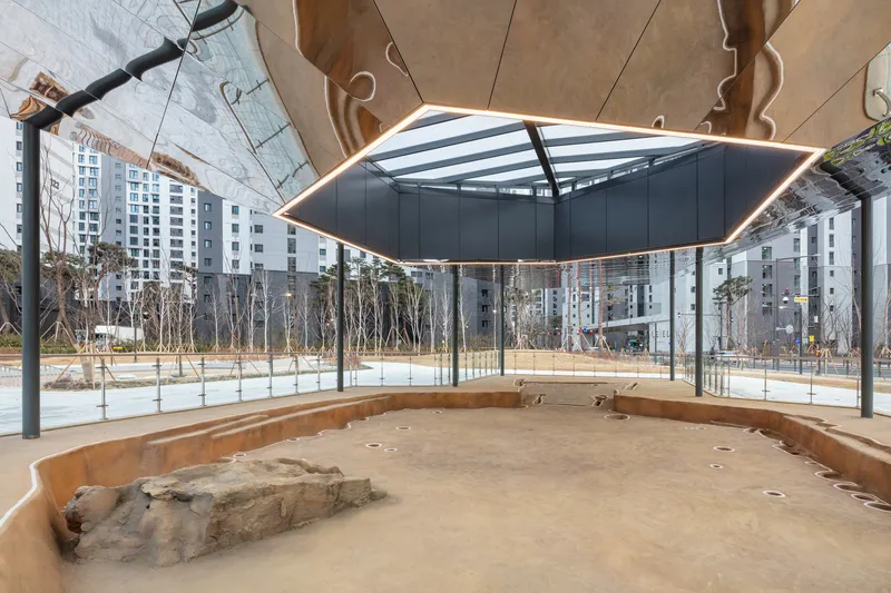 Interior view beneath the canopy showing exposed rock formations on the sand floor and glass perimeter walls