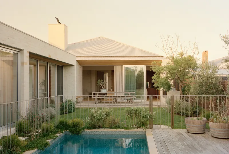 Rear terrace and pool framed by metal fencing with native grasses at dusk