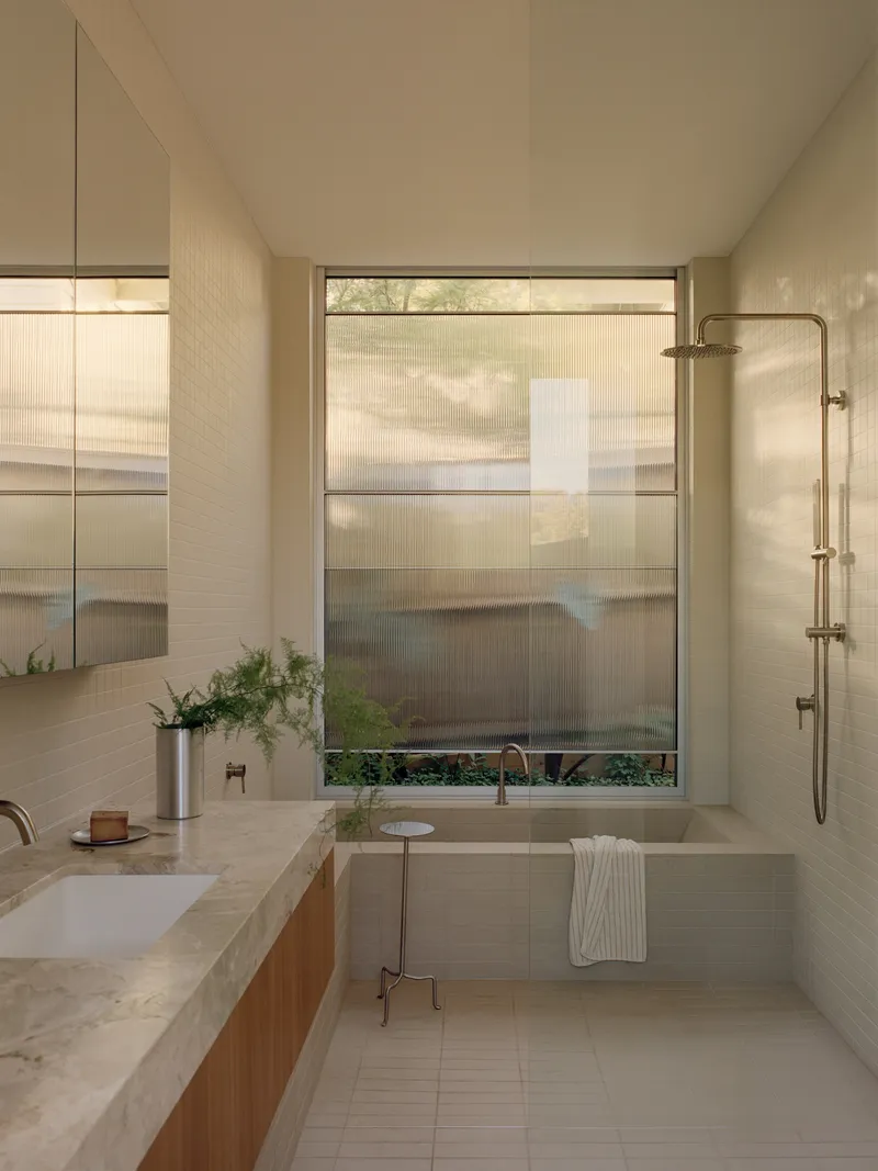 Bathroom with terrazzo vanity and translucent window shades filtering afternoon light