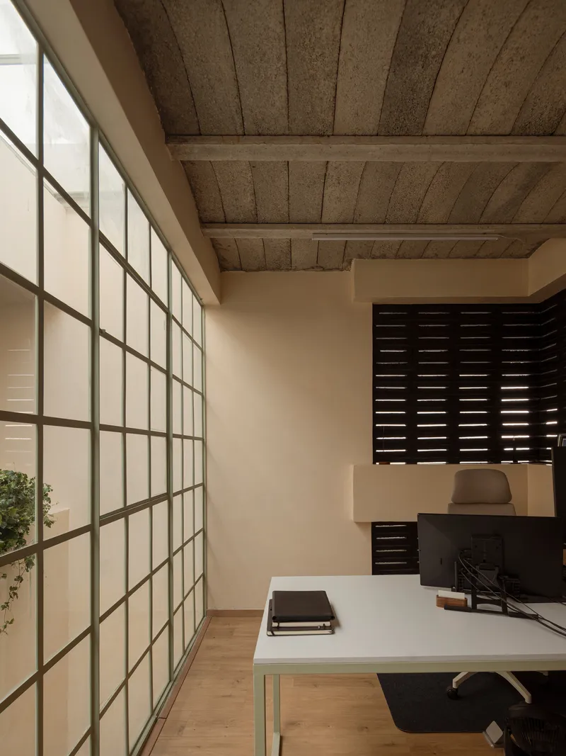 Workspace with translucent gridded glass wall, exposed timber ceiling beams and horizontal louvered screen