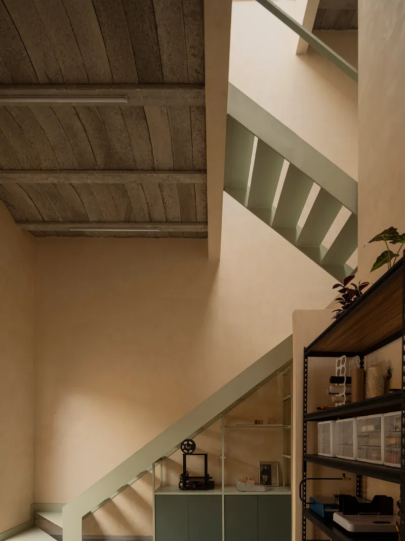 Stairwell with pale green handrail and storage shelving beneath the timber-beamed ceiling