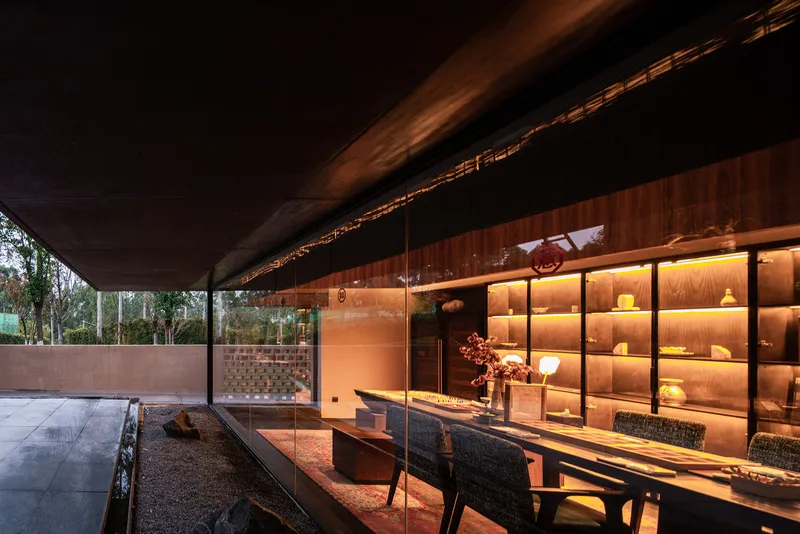 Covered terrace with exposed timber beams and illuminated display shelving beside exterior dining table