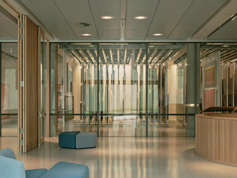 Lobby with glass partitions revealing timber baffle ceiling and polished concrete floor with blue upholstered seating