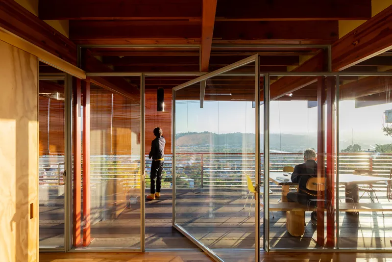 Glass sliding doors opening to terrace with two figures silhouetted against distant hills