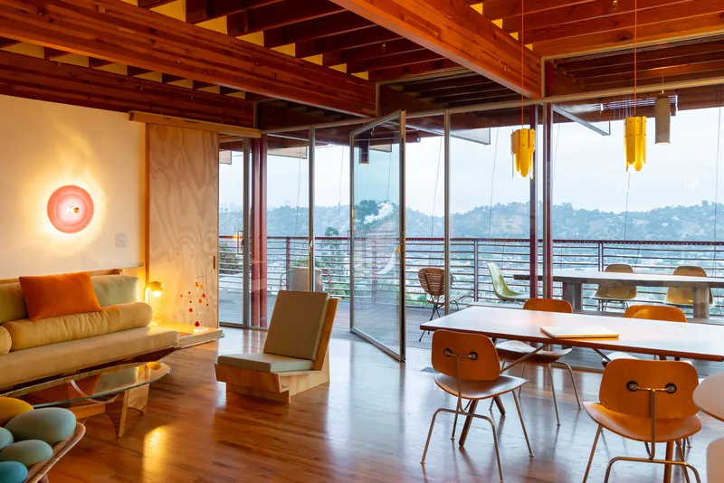 Dining space with exposed timber roof structure and sliding glass doors opening to terrace with valley views