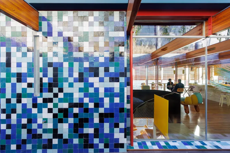 Glass wall looking into an interior space through a timber frame with pixelated tile facade