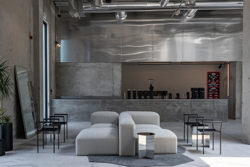 Reception area with concrete service counter and exposed ceiling ducts beneath reflective metal panels