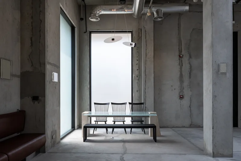 Marble table with metal chairs beneath a pendant light and tall window