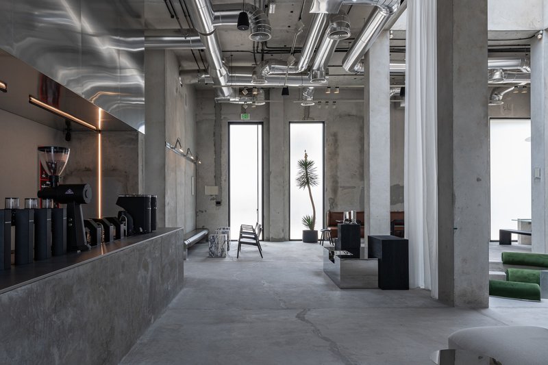 Open seating area with exposed mechanical systems overhead and concrete columns defining the space