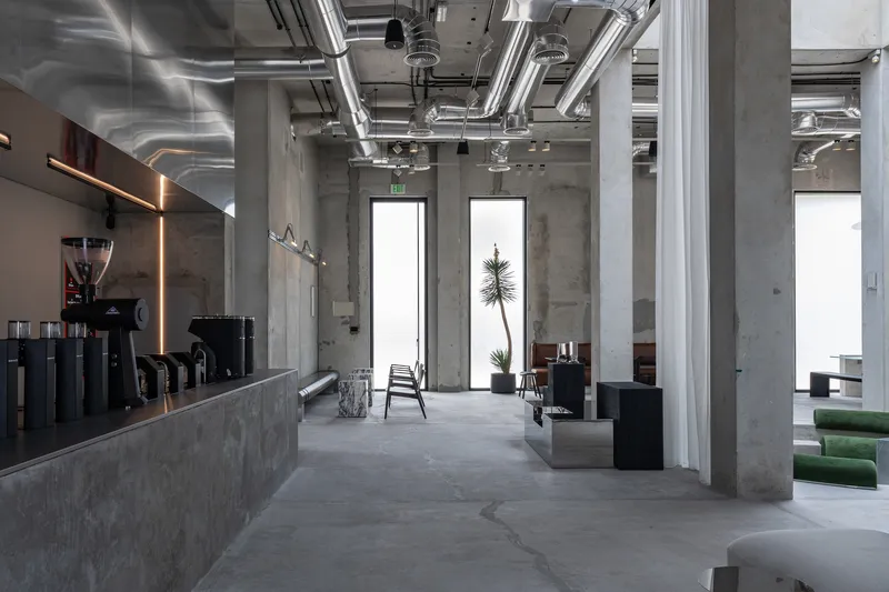 Open seating area with exposed mechanical systems overhead and concrete columns defining the space