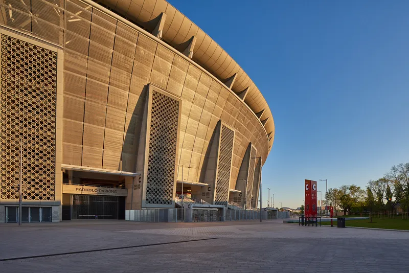 Curved facade with angled lattice panels and cantilevered roof in afternoon light