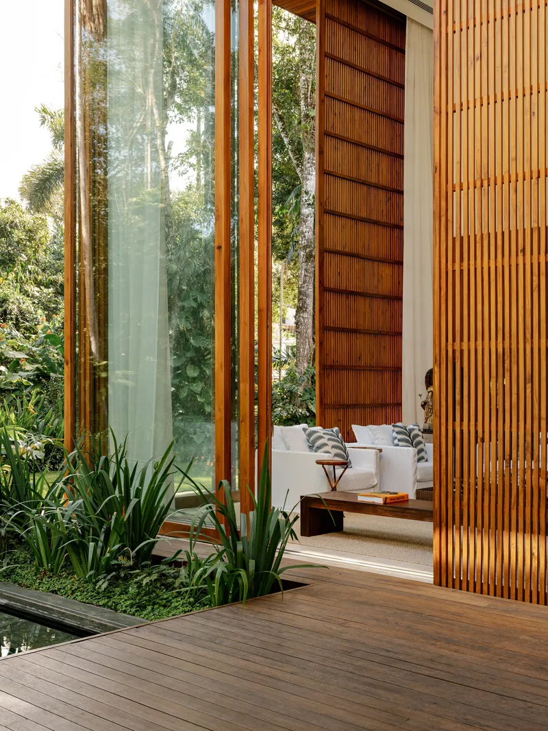 Covered timber deck with sliding louvered panels and vertical screen beside planted bed
