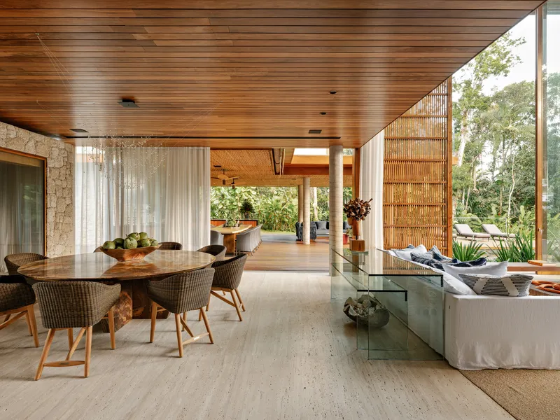 Open-plan dining and living space under timber ceiling with slatted screen dividing interior from terrace