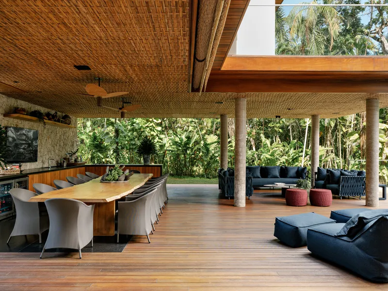 Open-air pavilion with woven bamboo ceiling, timber columns, and teak decking surrounded by tropical vegetation