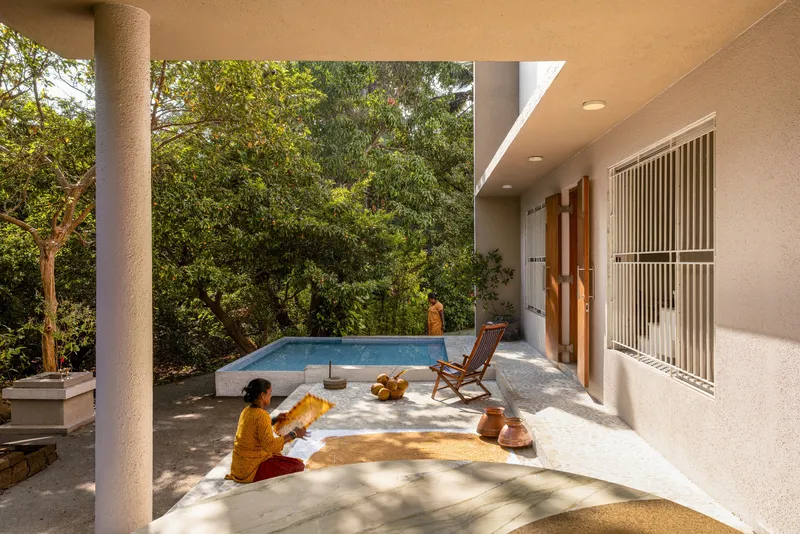 Covered terrace with circular column, raised pool edge and person seated in morning sun