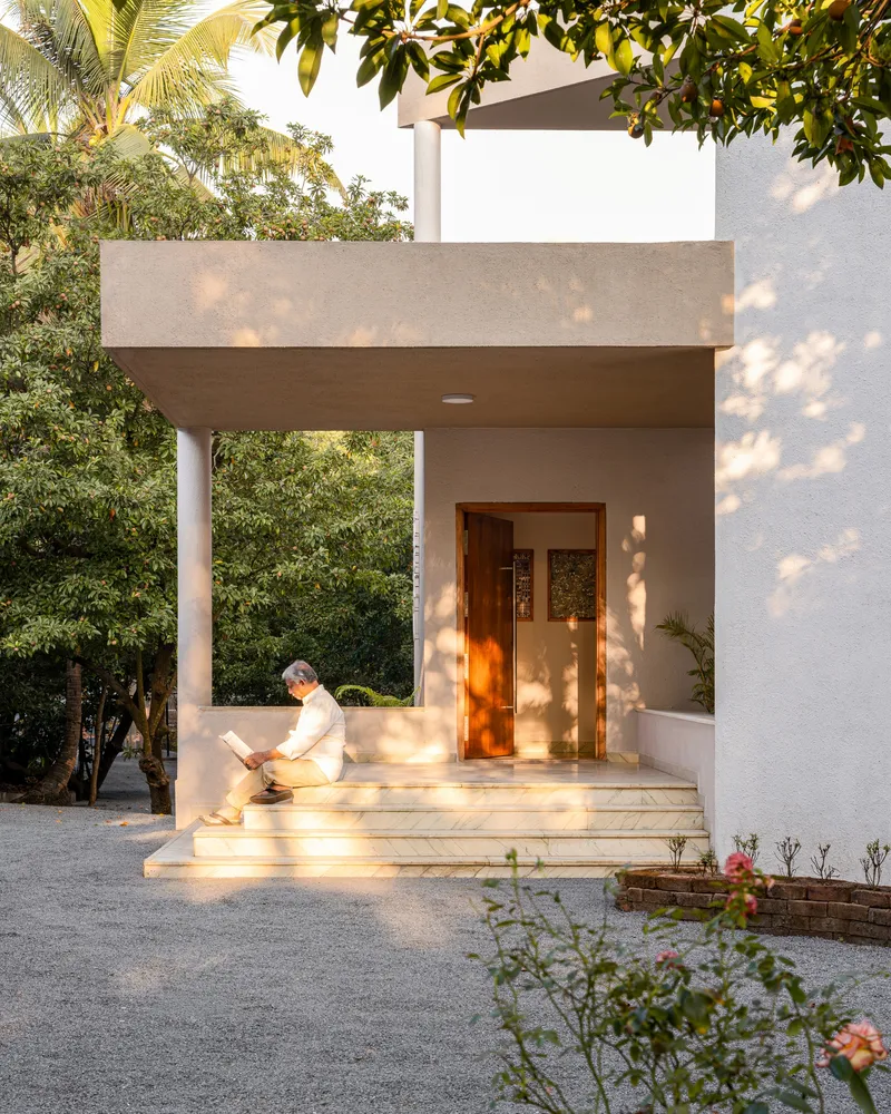 Entry portico with timber door, shallow steps and person reading in afternoon light