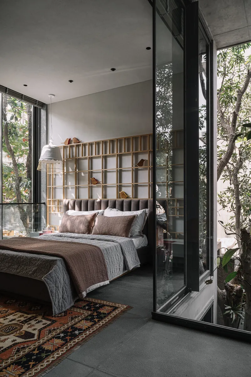 Bedroom with timber grid headboard opening to planted courtyard through floor-to-ceiling glazing