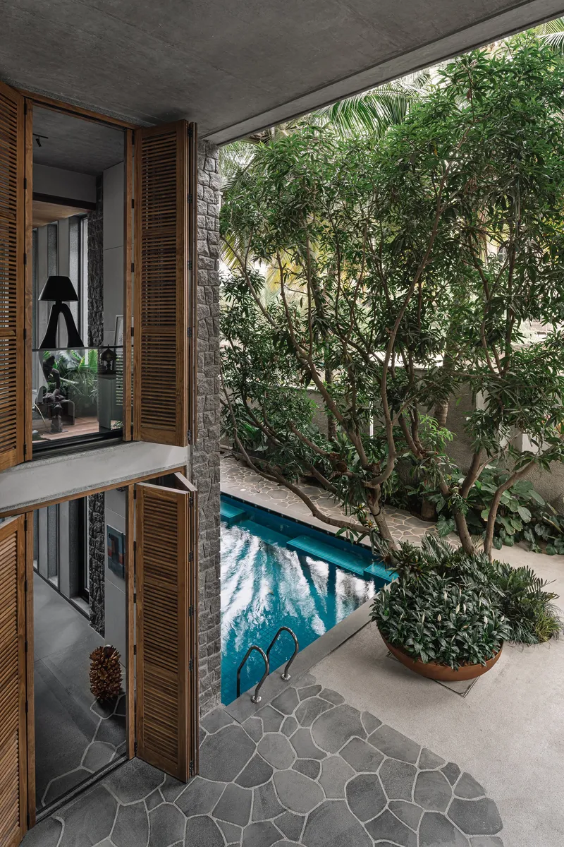 Internal courtyard with turquoise pool, mature tree, and timber louvered doors opening to interior