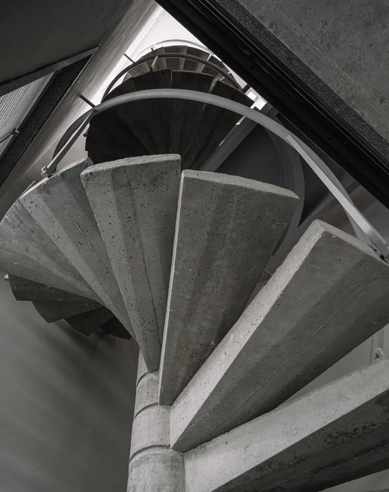Top-down view of spiraling concrete staircase with metal handrail wrapping around central column
