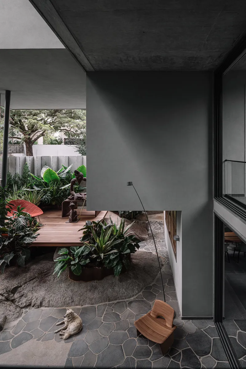 Interior view through glazed opening to courtyard with timber platform, potted plants and irregular stone paving
