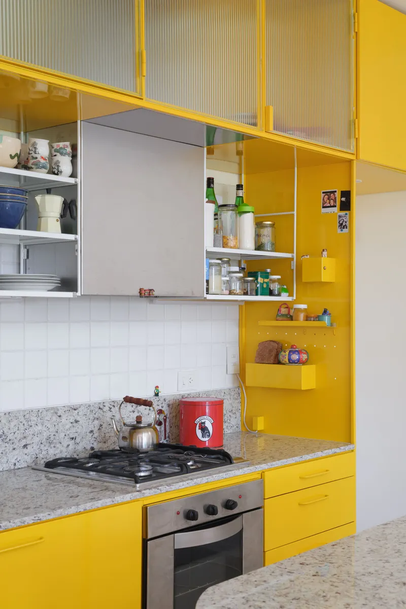 Kitchen with yellow lacquered cabinets, granite counter, gas cooktop and white tile backsplash